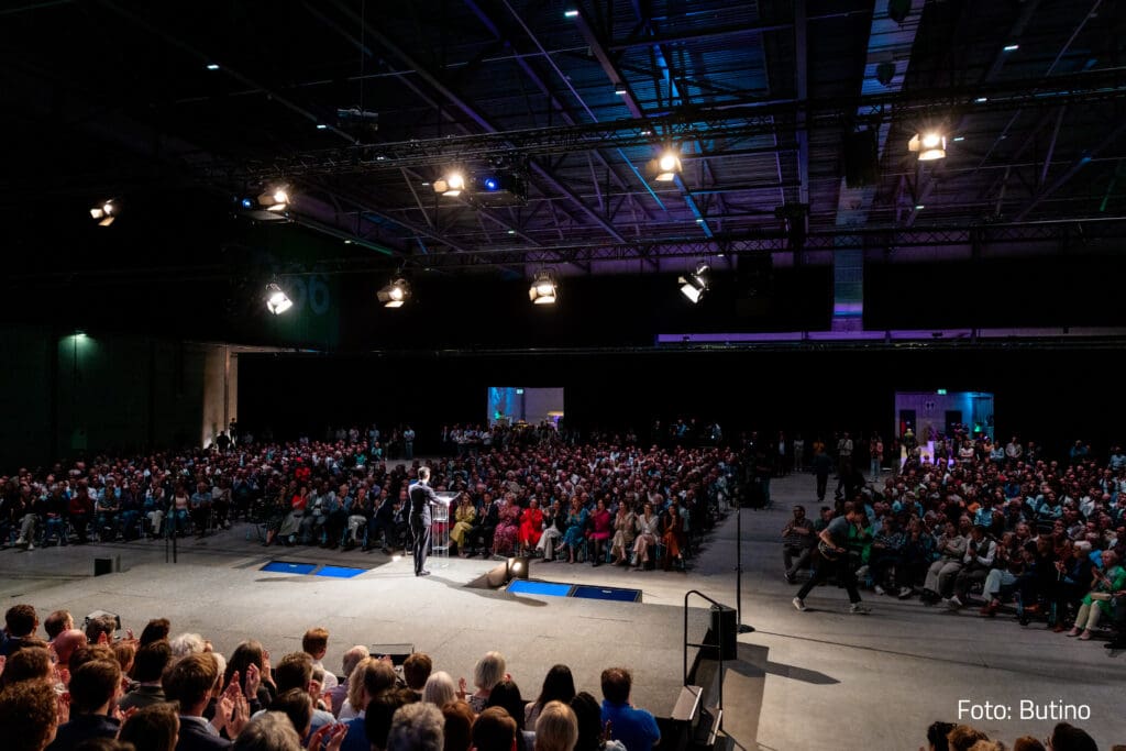 Een volle evenementenhal in Breepark tijdens een conferentie